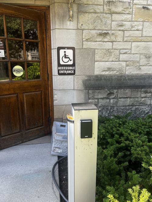 A brick building with an ADA button to open the door on the right of the picture