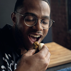 Kwame Onwuachi looking down, with food in his hand