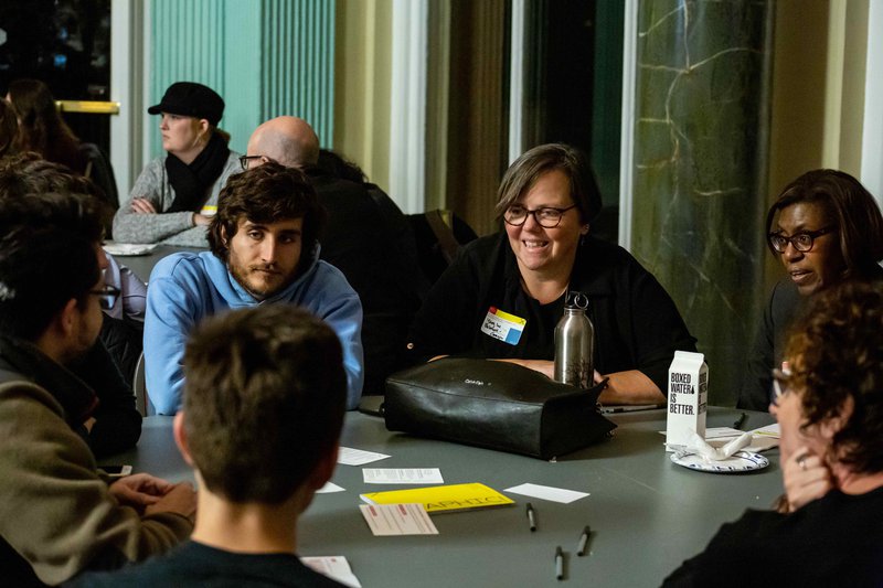 6 people of different ages sit around a round table talking to one another in the south short cultural center